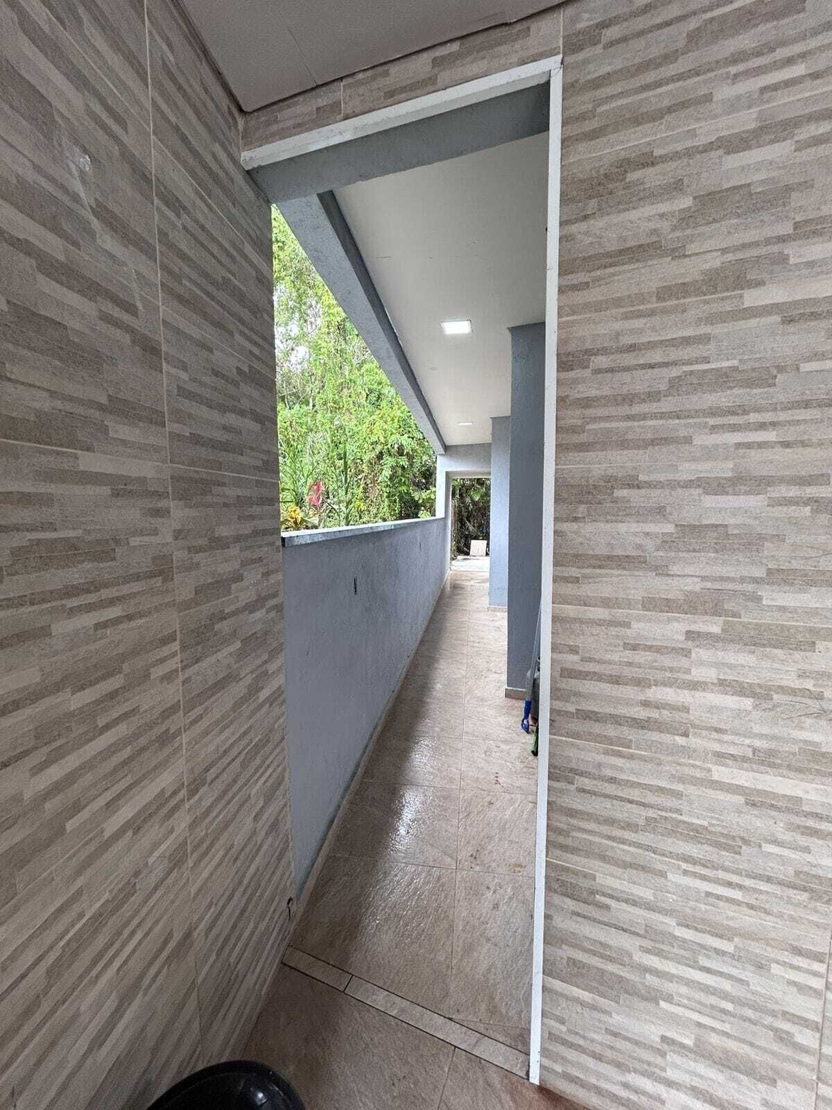 Un pasillo con suelo de baldosas y paredes que conduce a una habitación con ventana y puerta.
