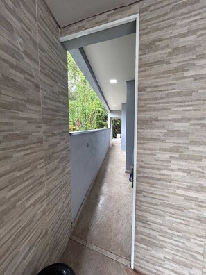 Un pasillo con suelo de baldosas y paredes que conduce a una habitación con ventana y puerta.