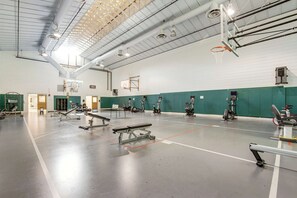 Ein Fitnessraum mit Trainingsgeräten, einem Basketballkorb und einer grünen Wand.