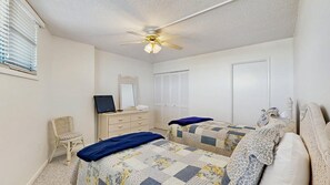 A bedroom with two beds, a dresser, a chair, a ceiling fan, and a window with blinds. - Sea Colony - 603N Edgewater House (Bethany Beach)