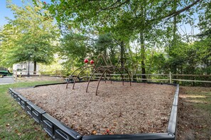 Ein Spielplatz mit einer Metallkletterkonstruktion und einem umzäunten Spielbereich.