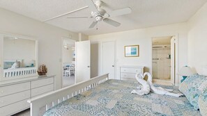 A bedroom with a bed, a dresser, a mirror, a ceiling fan, and a door leading to a bathroom. - Sea Colony - 603N Edgewater House (Bethany Beach)