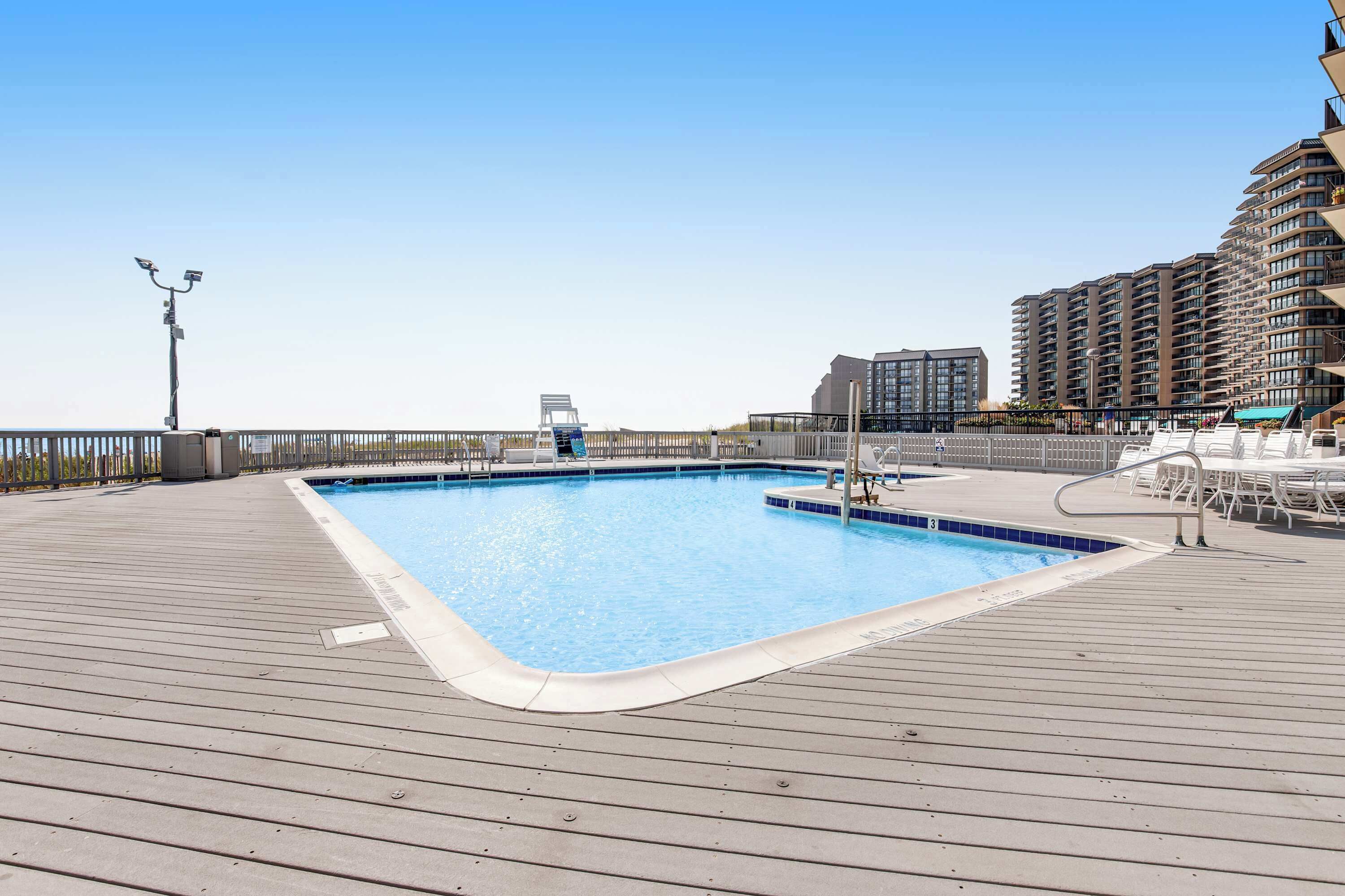 A swimming pool on a wooden deck with a view of high-rise buildings.