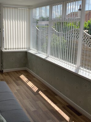 A corner room with a window, wooden flooring, and a white wall.