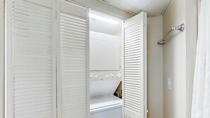 Un closet amplio con lavadora y secadora integradas, un espejo y un perchero.
