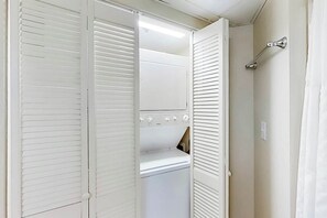 Ein begehbarer, weißer Kleiderschrank mit integrierter Waschmaschine und Trockner, einem Spiegel und einem Handtuchhalter.