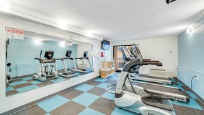 Un gimnasio con cintas de correr, elípticas y un espejo grande.