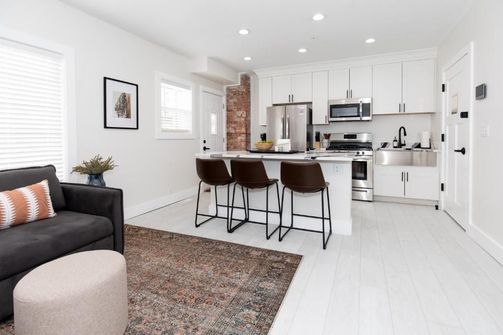 A modern kitchen with white cabinets, stainless steel appliances, and a central island with bar stools.