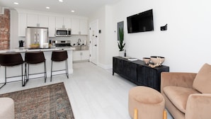 A modern kitchen with white cabinets, a black countertop, and a stainless steel refrigerator.