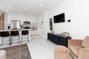 A modern kitchen with white cabinets, a black countertop, and a stainless steel refrigerator. - The Inn at 201 Fulton St. (Sandusky)