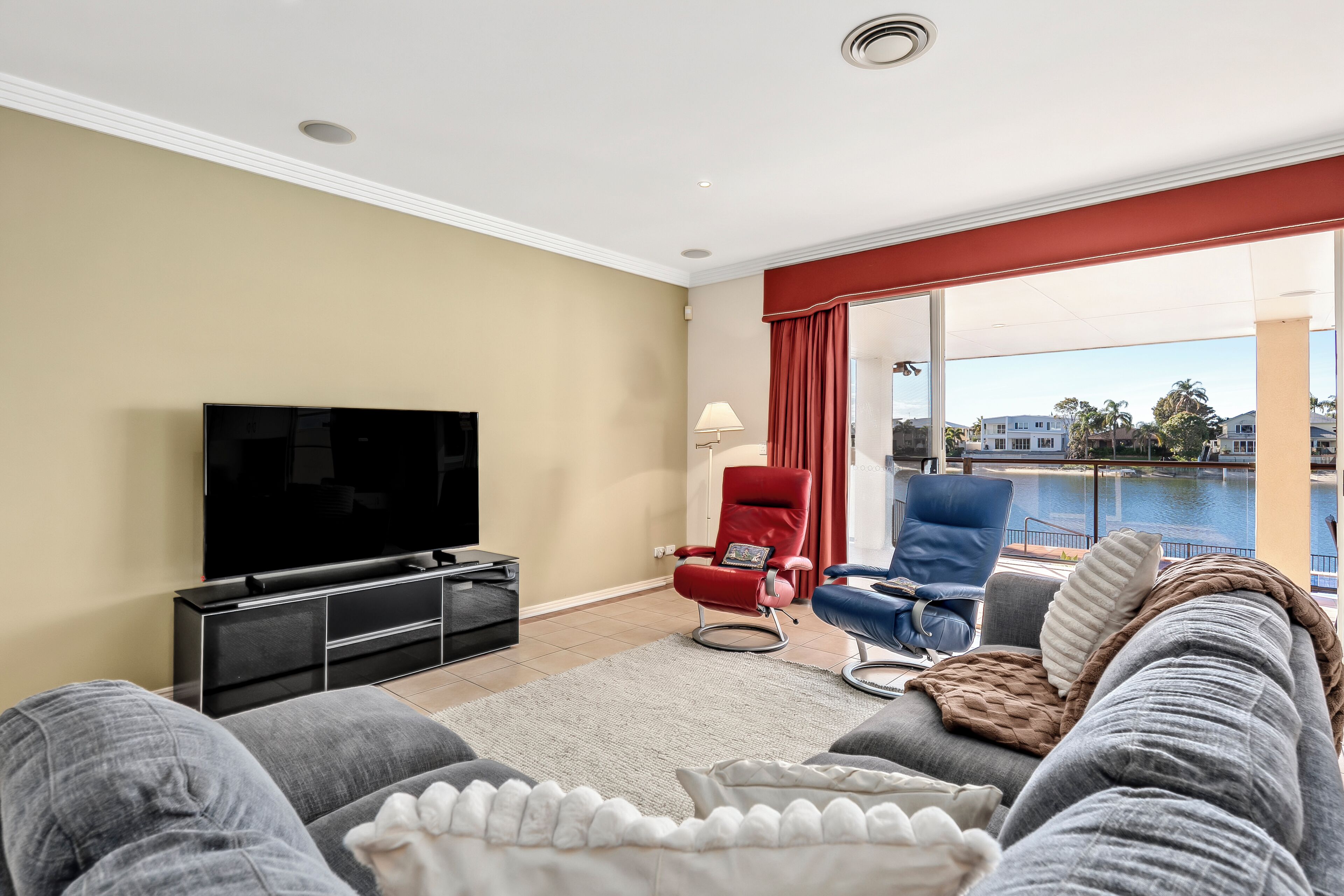 Ein Wohnzimmer mit Flachbildfernseher, einem roten Sessel, einem blauen Sessel und einer Couch.