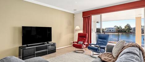 Ein Wohnzimmer mit Flachbildfernseher, einem roten Sessel, einem blauen Sessel und einer Couch.