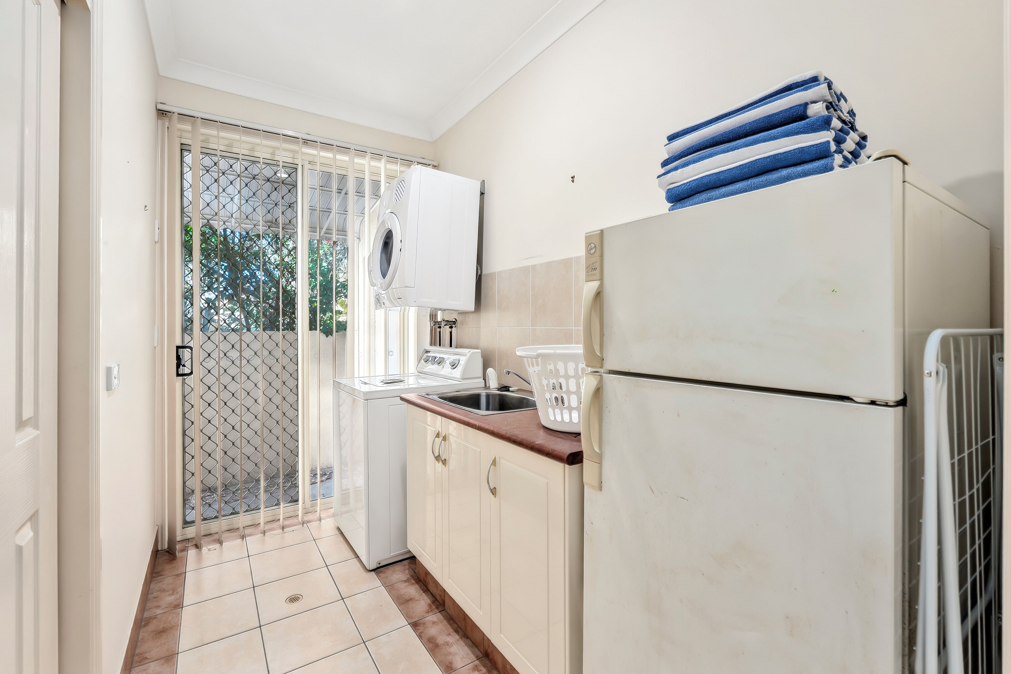 A compact kitchen with a refrigerator, a washing machine, and a sink.