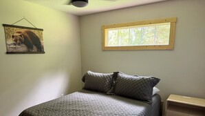 Ein Schlafzimmer mit einem Bett, einem Nachttisch, einem Fenster und einem Wandbild.