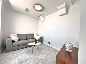 Una sala de estar moderna con un sofá gris, una mesita redonda y un jarrón decorativo.