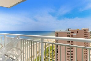 A balcony with a view of the beach and ocean, white railings, and a chair. - Carolinian Beach Resort 1935 (Myrtle Beach)