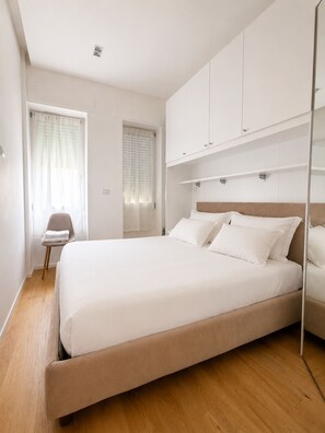 Ein Schlafzimmer mit einem großen Bett, einem Sessel und eingebauten Schränken.