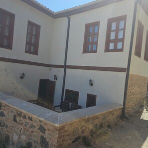 A building with multiple windows, a stone wall, and a paved area.