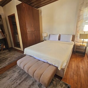 Une chambre à coucher avec un grand lit, une armoire en bois et un banc.