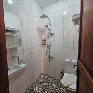 Une salle de bain équipée d’une douche, d’un lavabo, de toilettes et d’un sol carrelé avec un motif géométrique.