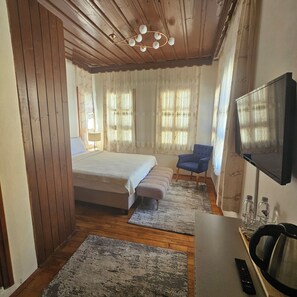 Une chambre à coucher comprenant un lit, une chaise, un téléviseur et une bouilloire.