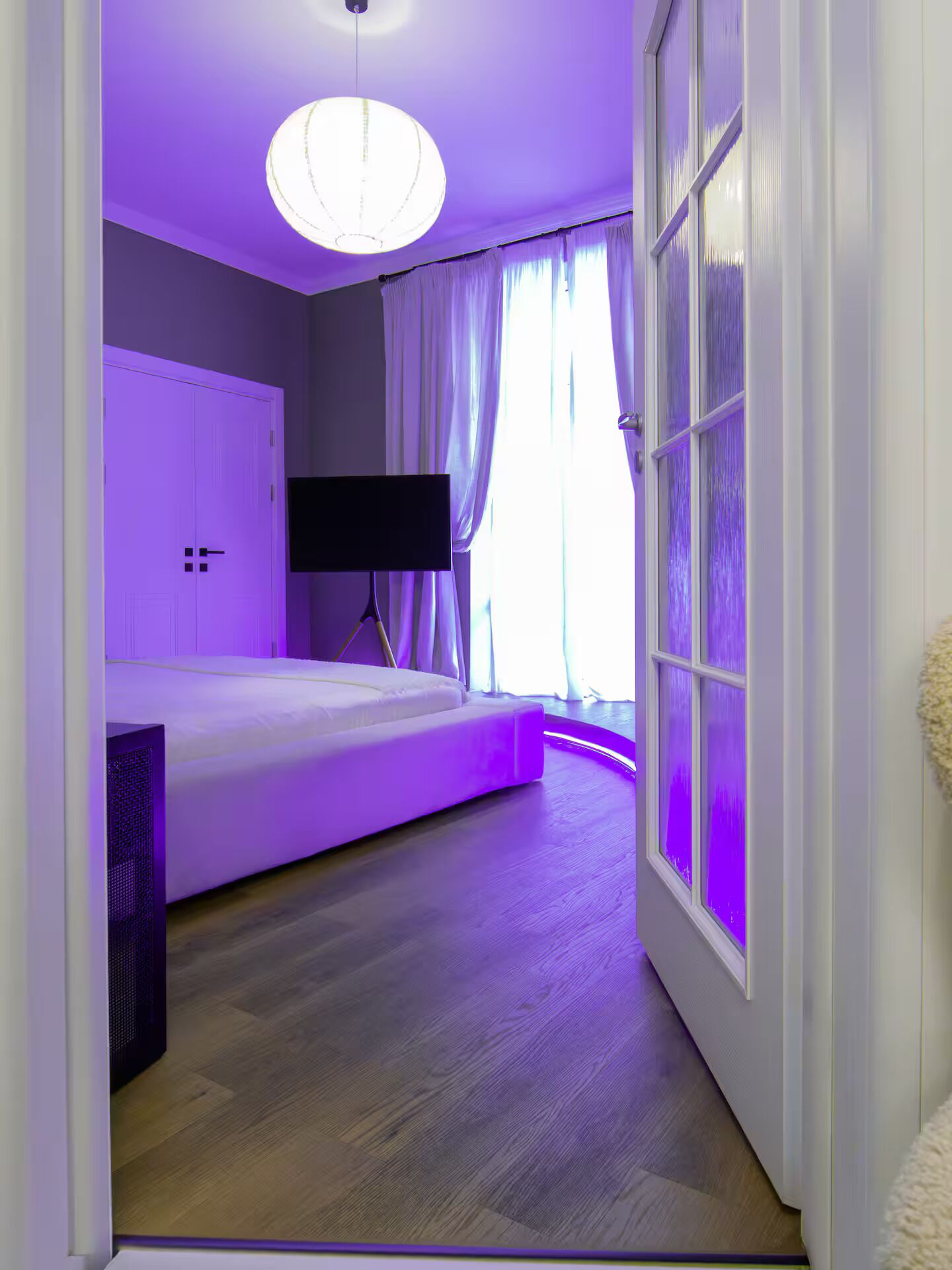 Ein Schlafzimmer mit einem Bett, einem Fernseher und einem fensterbepflanzten Fenster.