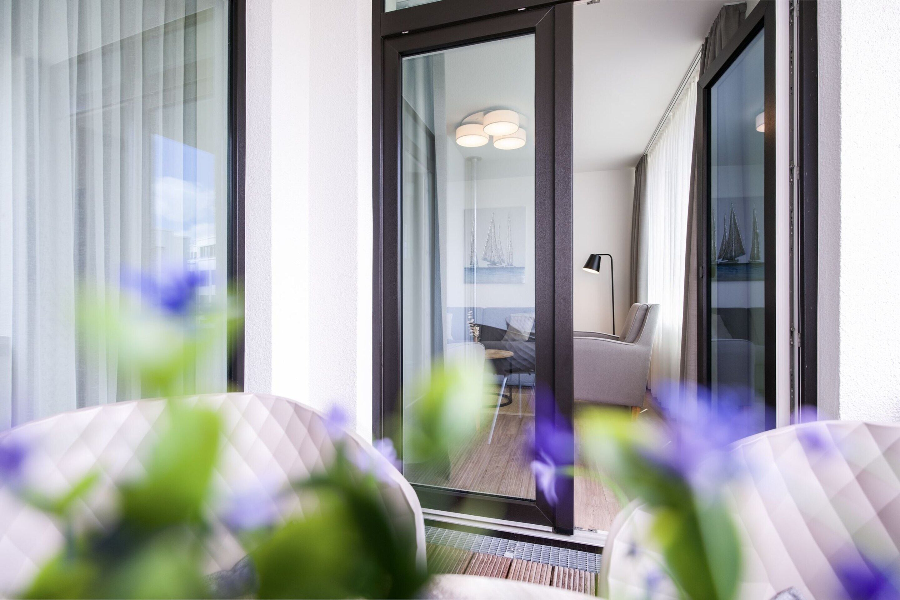 Un intérieur moderne avec une porte vitrée donnant sur un balcon, un canapé et une lampe.
