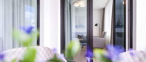 Un intérieur moderne avec une porte vitrée donnant sur un balcon, un canapé et une lampe.