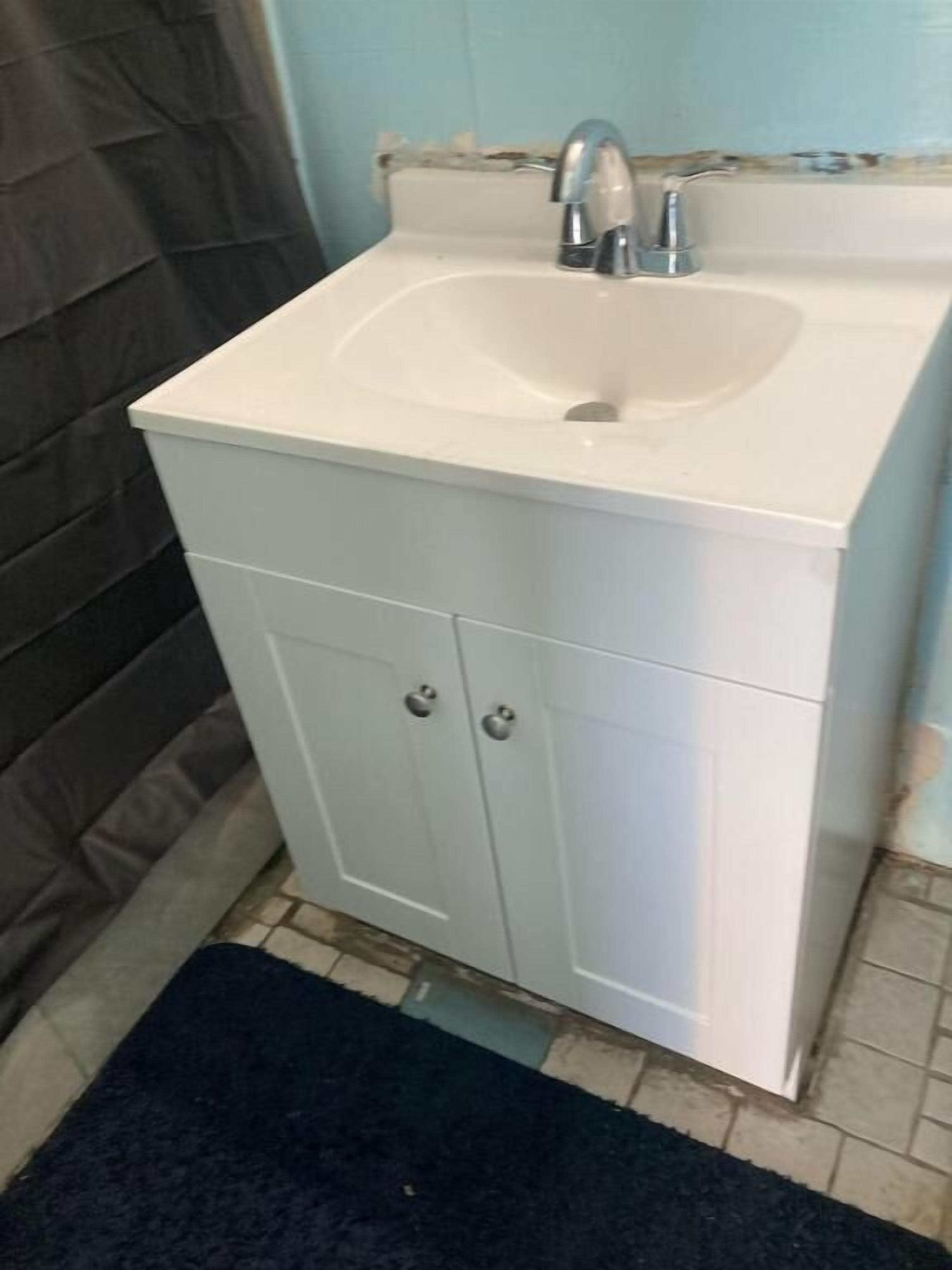 A bathroom with a white sink, a mirror, and a cabinet.