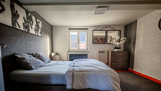 A bedroom with a bed, a dresser, a chair, and a window.