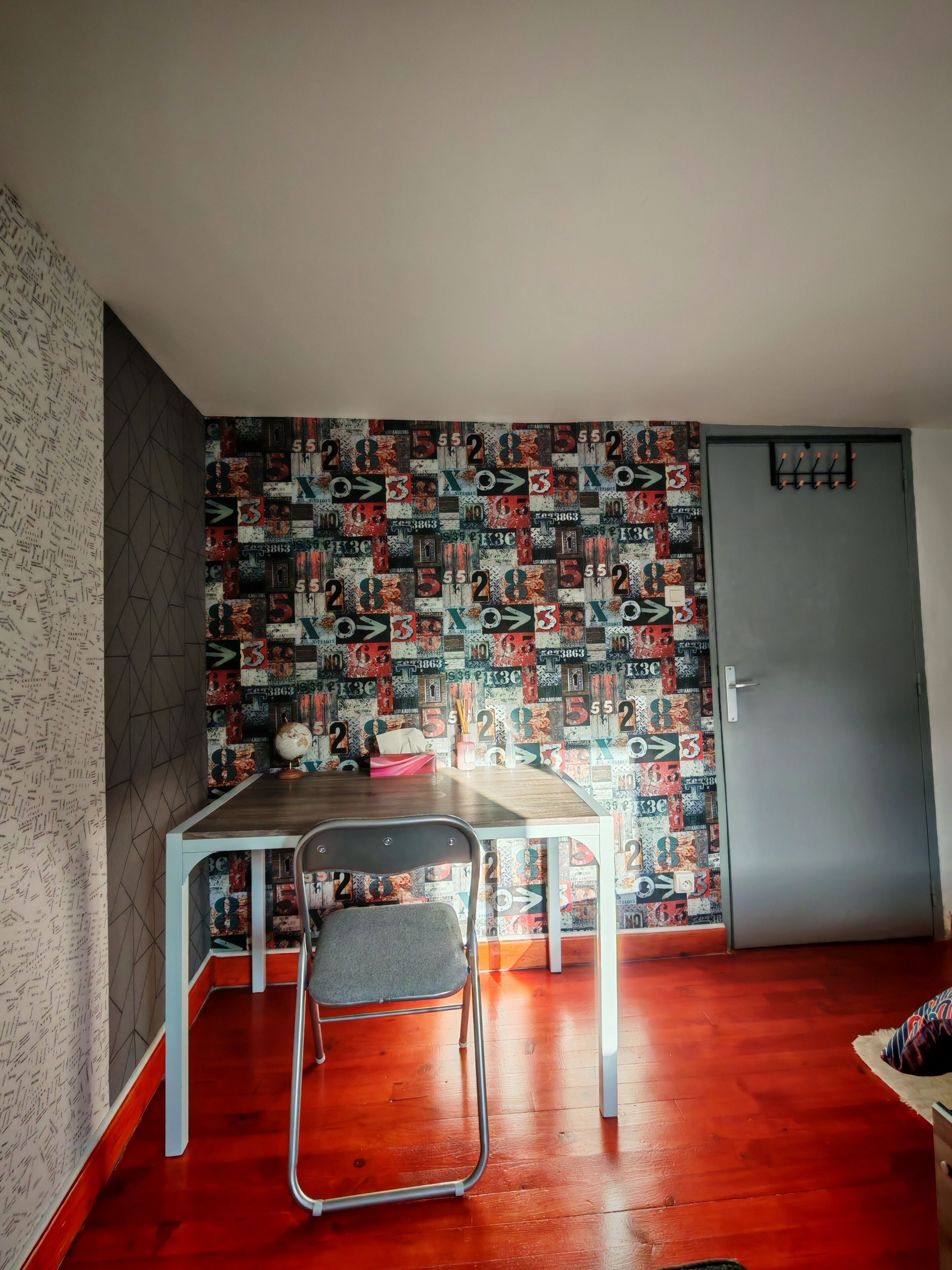 Une pièce comprenant une table à manger, une chaise, un globe terrestre et un mur décoré de motifs.