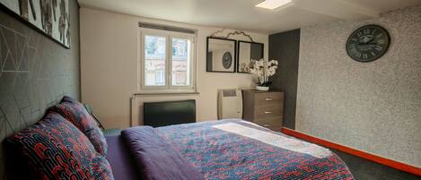 A bedroom with a bed, a dresser, a clock, and a window.