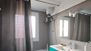 A bathroom with a bathtub, a sink with a mirror, and a green floor mat.