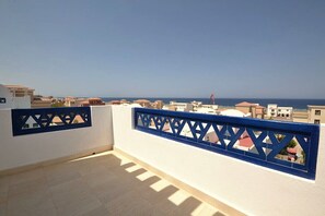 Ein Balkon mit Blick auf das Meer und andere Gebäude.