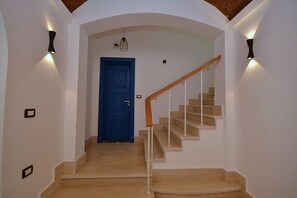 Eine Treppe mit Holzgeländer und beigefarbenen Stufen, die zu einer blauen Tür führt.