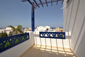 Ein Balkon mit Blick auf das Meer und weiße Gebäude.