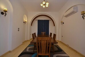Ein Essbereich mit Holztisch und Stühlen, einem Rundbogen und Wandleuchten.