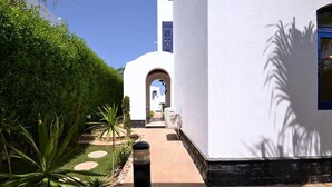 A pathway leading to a building with a white facade and an arched entrance. - Luxury 4-Bedroom Villa for Rent in Amaros. (Red Sea Governorate)