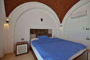 Ein Schlafzimmer mit einem Bett, einem Nachttisch, einer Klimaanlage und einer Backsteinwand.