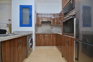 Eine Küche mit Holzschränken, Edelstahlgeräten und einem Fenster mit blauer Umrandung.