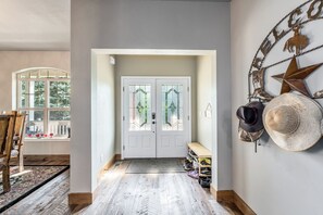 Een hal met een houten vloer, een witte deur met glaspanelen en een sterdecoratie aan de muur.