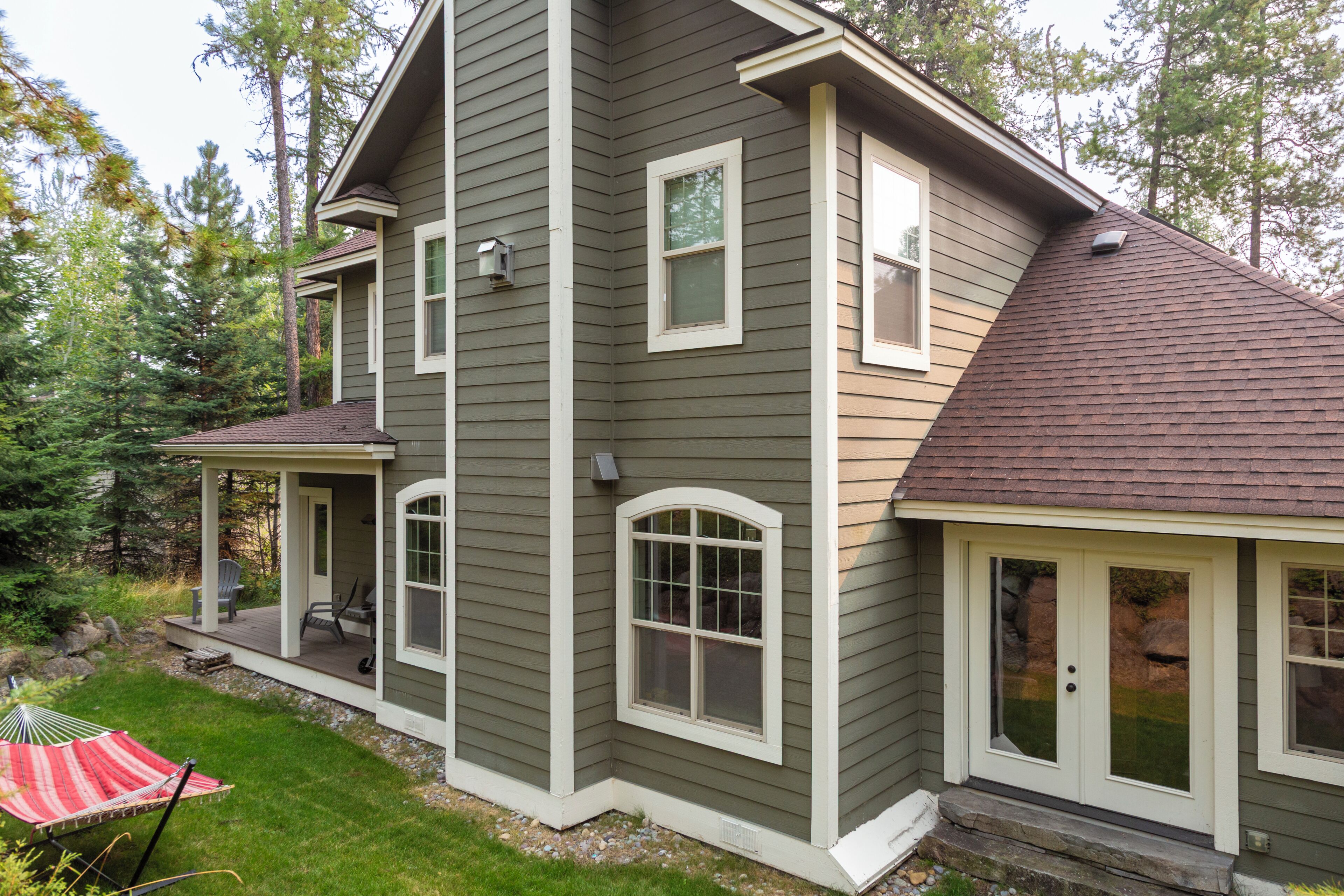 A two-story house with a covered porch and a red and white striped umbrella.
