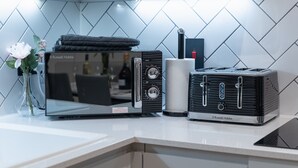 A kitchen with a modern microwave, toaster, and a vase with flowers on the counter. - 1-Bed Flat 7 Min to Piccadilly Station (Manchester)