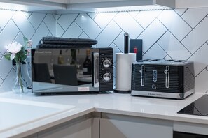 A kitchen with a modern microwave, toaster, and a vase with flowers on the counter. - 1-Bed Flat 7 Min to Piccadilly Station (Manchester)