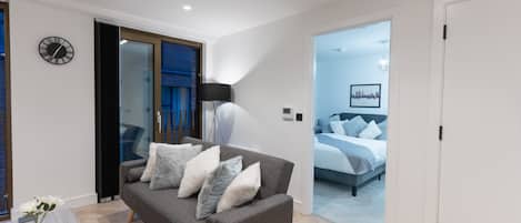 Un salón moderno con un sofá gris, una lámpara de pie negra y un reloj de pared.