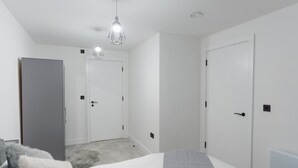 A bedroom with a bed, a wardrobe, and a door. - 1-Bed Flat 7 Min to Piccadilly Station (Manchester)