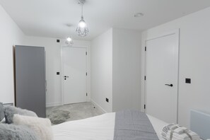 A bedroom with a bed, a wardrobe, and a door. - 1-Bed Flat 7 Min to Piccadilly Station (Manchester)
