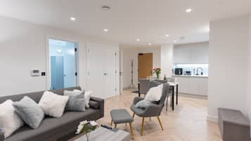 A modern living room with a grey sofa, a coffee table, and a dining area with a grey chair and table.