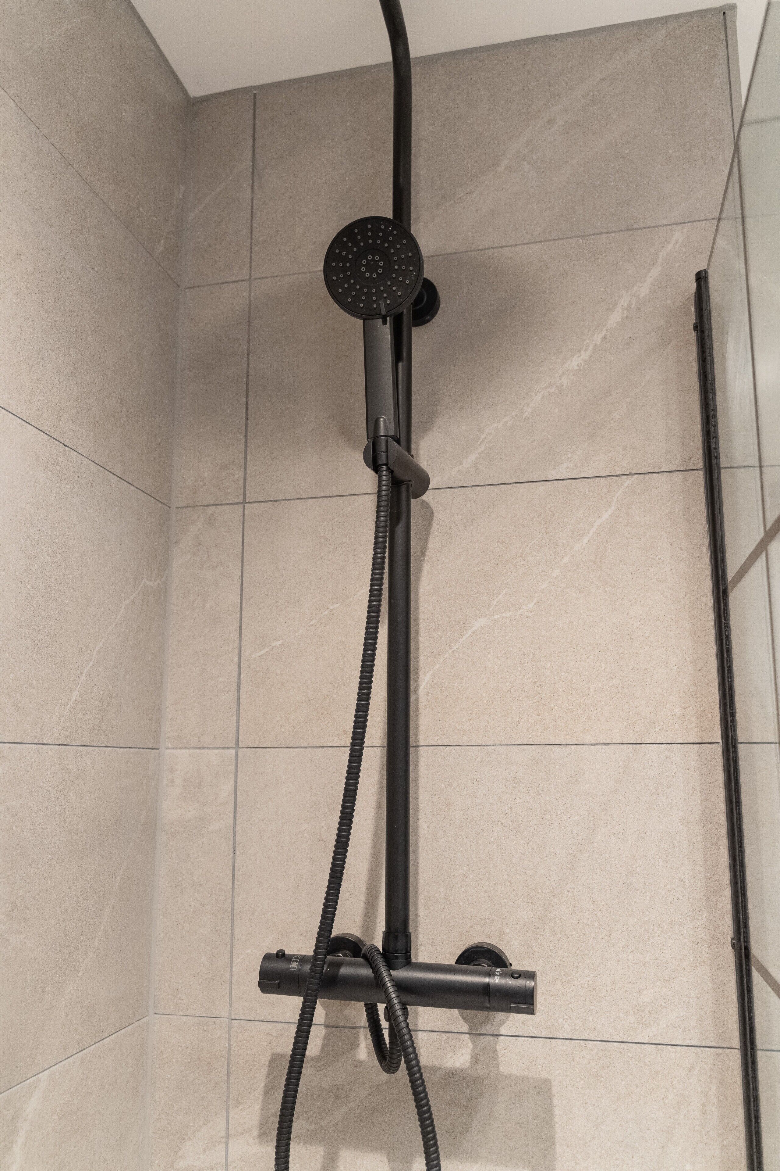 A shower with a handheld showerhead and a flexible hose.