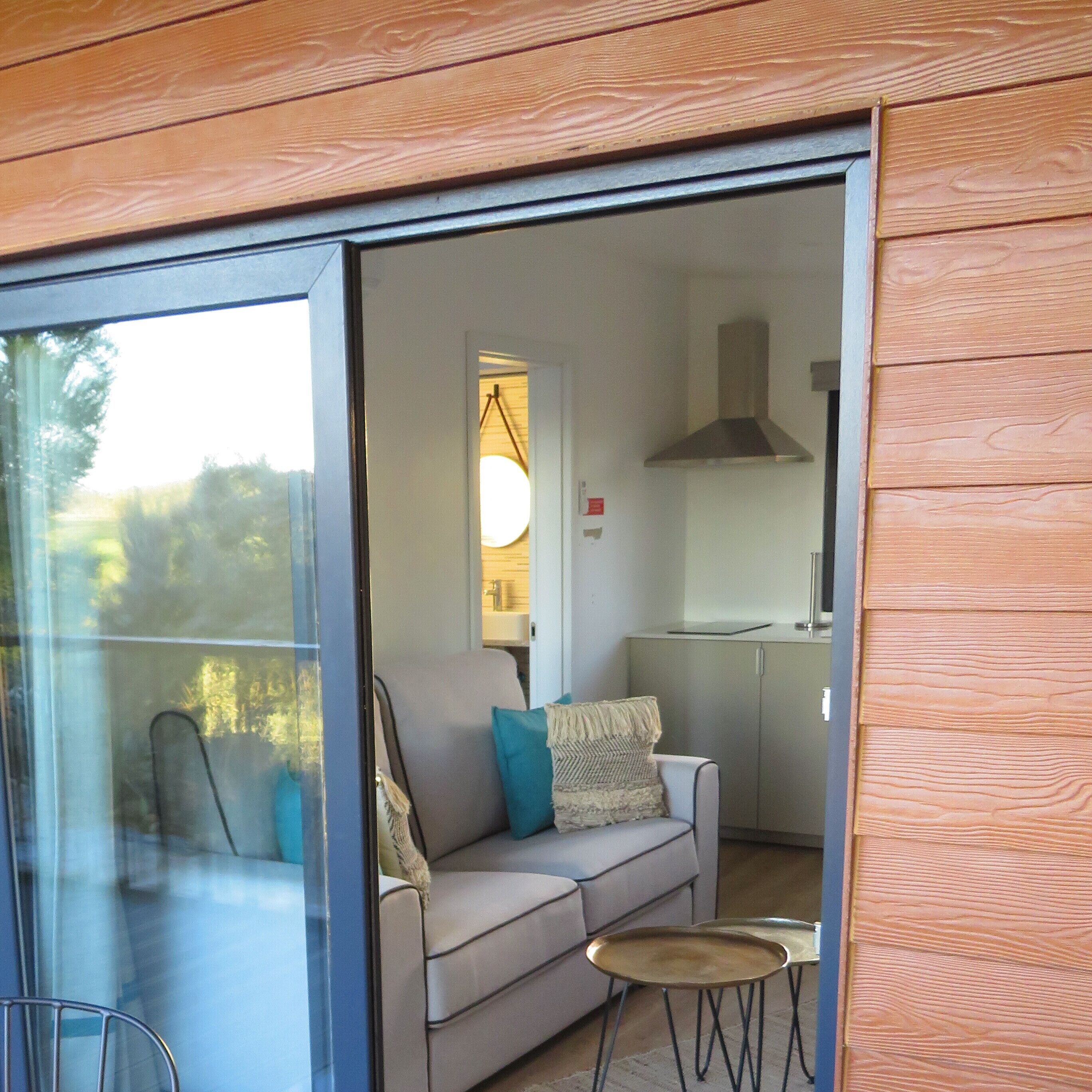 Un intérieur moderne avec une porte vitrée donnant sur un balcon, un canapé avec des coussins et une petite table ronde.